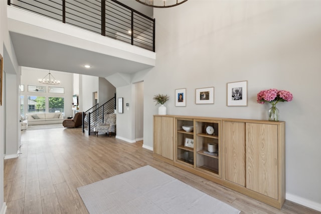 entrance foyer with a high ceiling, light hardwood / wood-style floors, and an inviting chandelier