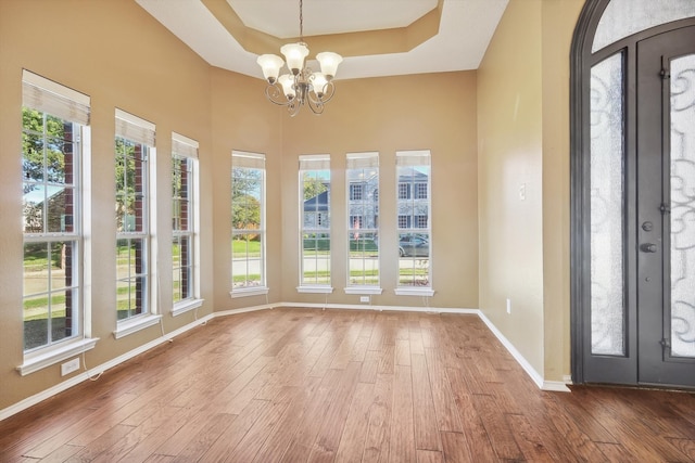 unfurnished sunroom with a notable chandelier and a tray ceiling