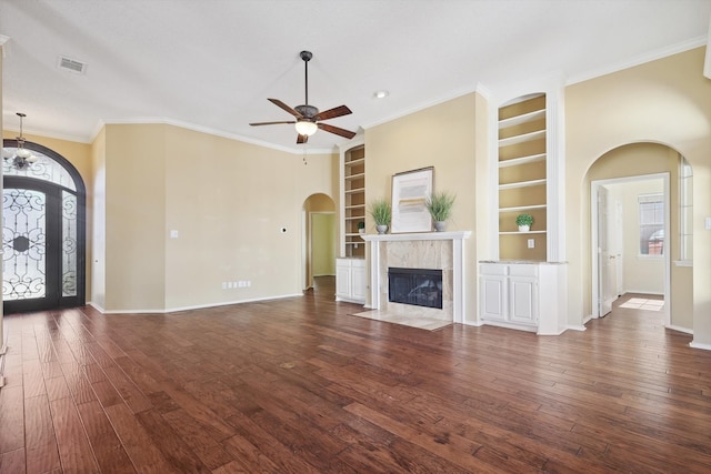 unfurnished living room with built in shelves, ceiling fan, dark hardwood / wood-style flooring, and ornamental molding