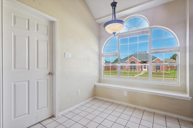 spare room with light tile patterned flooring and vaulted ceiling