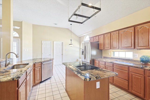 kitchen with sink, an island with sink, a textured ceiling, vaulted ceiling, and appliances with stainless steel finishes