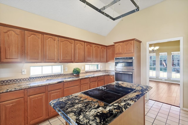 kitchen featuring light wood-type flooring, stainless steel double oven, black electric cooktop, and a healthy amount of sunlight