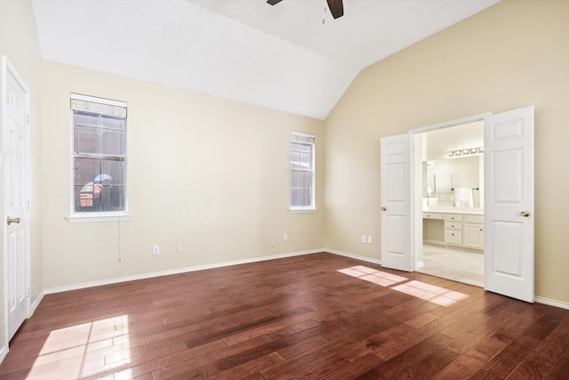 unfurnished bedroom featuring dark wood-type flooring, ensuite bathroom, vaulted ceiling, ceiling fan, and built in desk