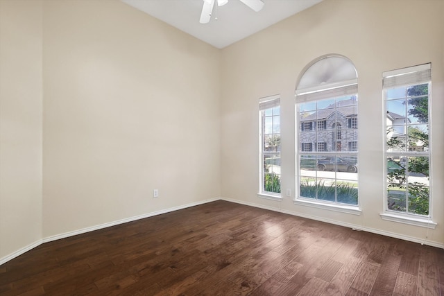 unfurnished room with dark hardwood / wood-style flooring, ceiling fan, plenty of natural light, and a towering ceiling