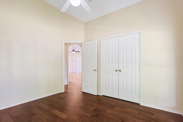 unfurnished bedroom featuring ceiling fan, a closet, high vaulted ceiling, and dark wood-type flooring