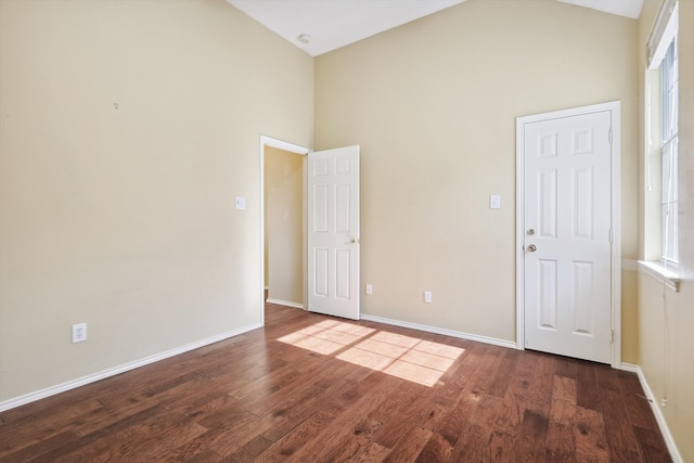 empty room with dark hardwood / wood-style floors, high vaulted ceiling, and a healthy amount of sunlight