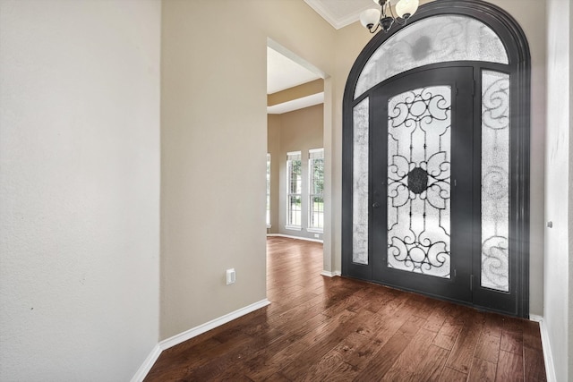 entryway with dark hardwood / wood-style floors, crown molding, and a chandelier