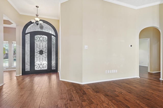 foyer entrance with a chandelier, crown molding, a towering ceiling, and dark wood-type flooring