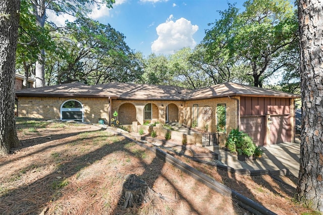 view of front of property featuring driveway, brick siding, board and batten siding, and an attached garage