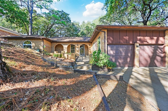 view of front of home featuring board and batten siding, brick siding, driveway, and a garage