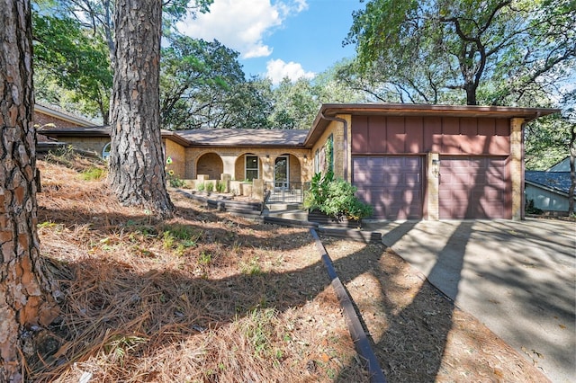 view of front facade with covered porch, board and batten siding, concrete driveway, and a garage