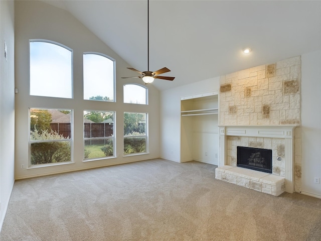 unfurnished living room featuring high vaulted ceiling, light colored carpet, a large fireplace, and ceiling fan