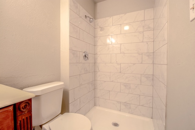 bathroom with a tile shower and toilet