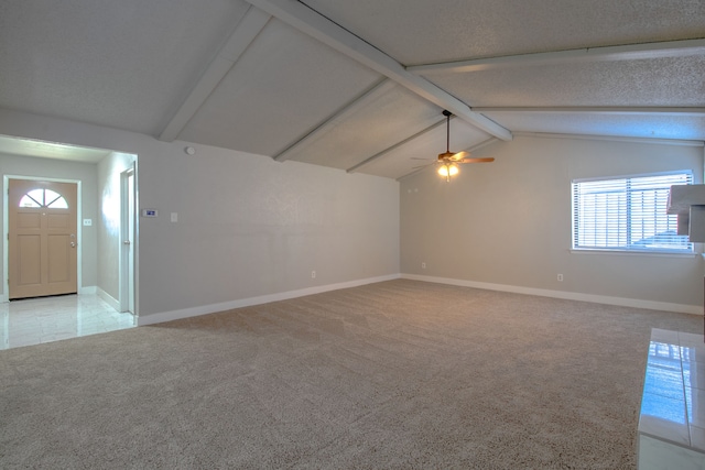 carpeted empty room with ceiling fan, lofted ceiling with beams, and a textured ceiling