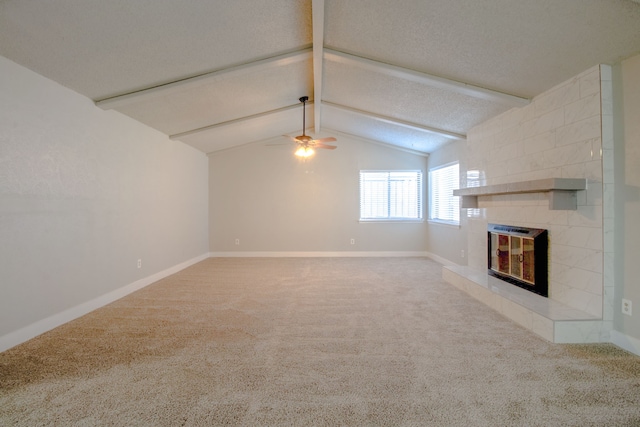 unfurnished living room featuring ceiling fan, lofted ceiling with beams, carpet floors, and a fireplace