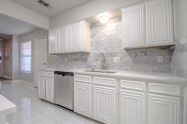 kitchen with backsplash, white cabinetry, sink, and stainless steel dishwasher