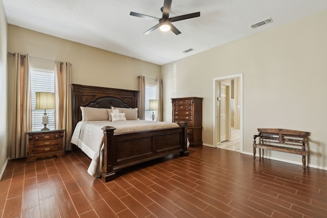 bedroom with ceiling fan, dark hardwood / wood-style flooring, ensuite bathroom, and a textured ceiling