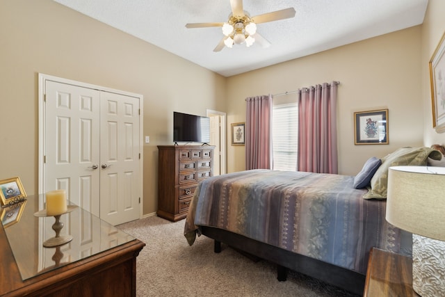 bedroom featuring ceiling fan, a closet, light carpet, and a textured ceiling