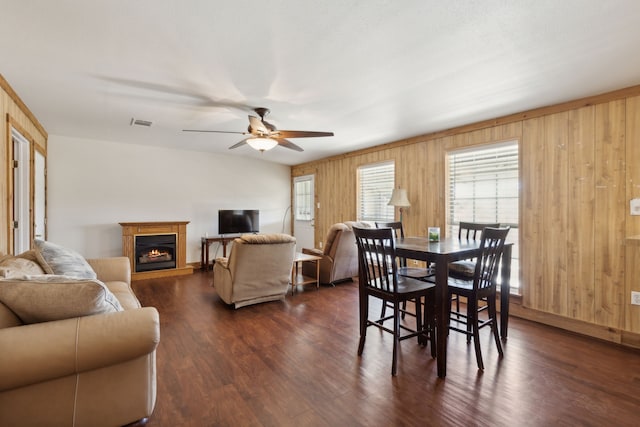 dining area with ceiling fan, wood walls, and dark hardwood / wood-style flooring