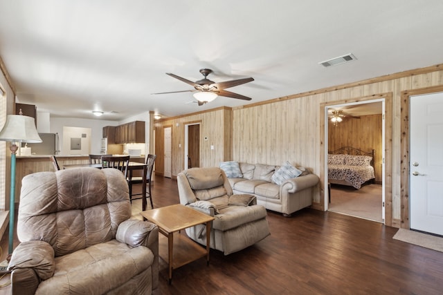 living room with wood-type flooring, ceiling fan, and wood walls