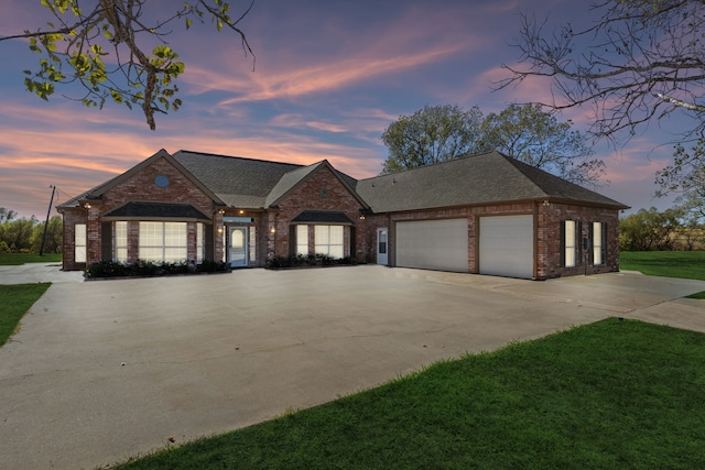 view of front facade featuring an attached garage, concrete driveway, brick siding, a front lawn, and roof with shingles