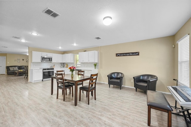 dining space featuring light hardwood / wood-style flooring and a textured ceiling