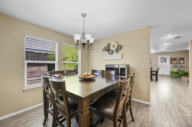 dining room with wood-type flooring and an inviting chandelier