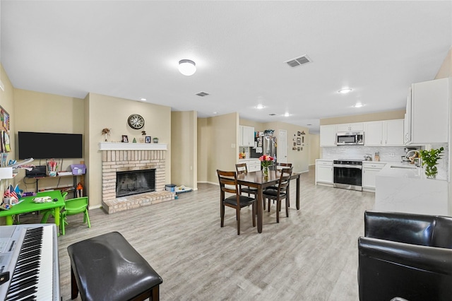 dining room featuring a fireplace, light hardwood / wood-style flooring, and sink