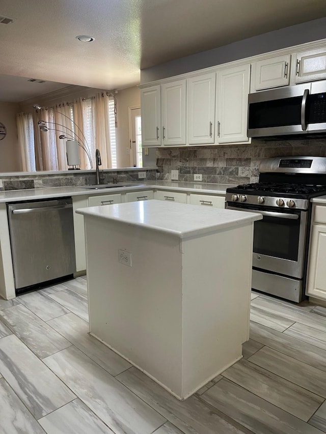 kitchen featuring white cabinets, sink, light wood-type flooring, a kitchen island, and stainless steel appliances