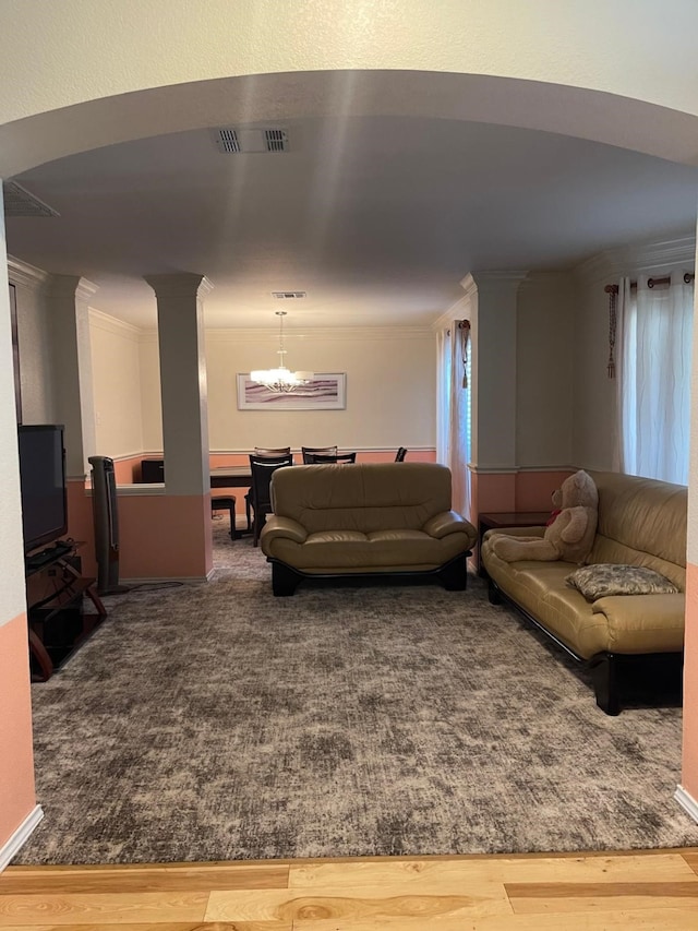 living room with wood-type flooring, ornamental molding, and a chandelier