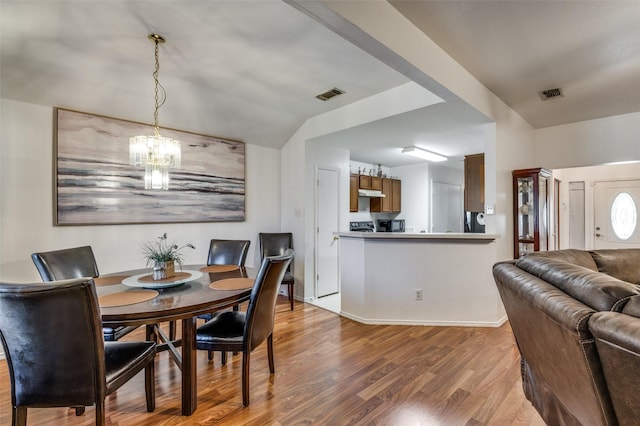 dining space with hardwood / wood-style flooring, a notable chandelier, and lofted ceiling