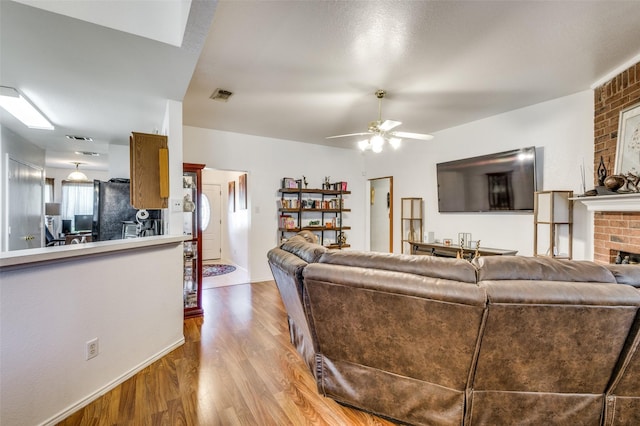 living room featuring ceiling fan, light hardwood / wood-style floors, and a fireplace