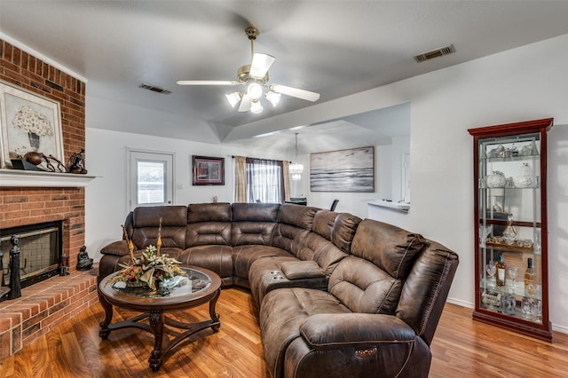 living room featuring ceiling fan, a fireplace, and hardwood / wood-style flooring