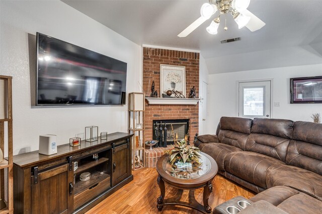 living room with a fireplace, light hardwood / wood-style floors, ceiling fan, and lofted ceiling