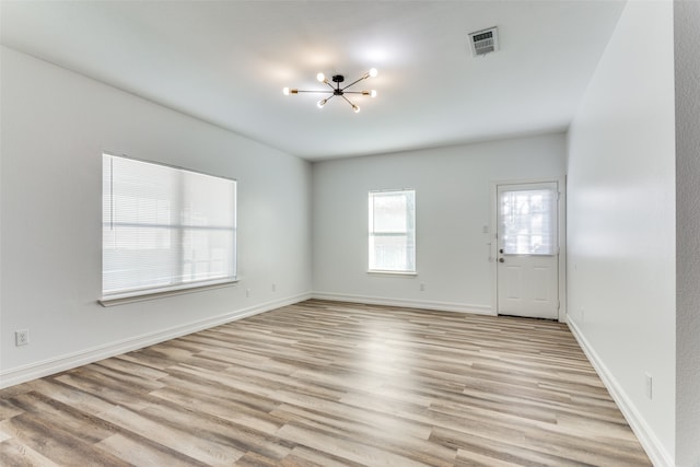 unfurnished room featuring light hardwood / wood-style flooring and a notable chandelier