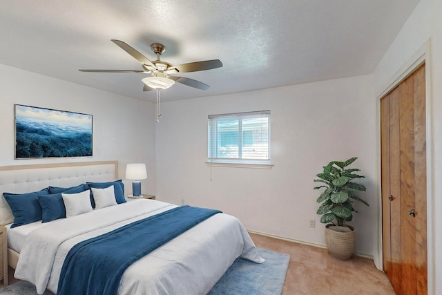 bedroom featuring ceiling fan, light colored carpet, a textured ceiling, and a closet