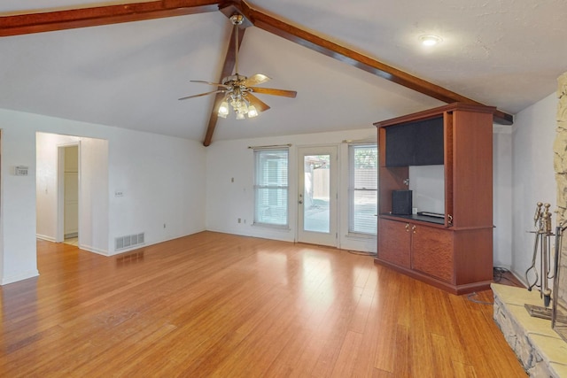 unfurnished living room featuring high vaulted ceiling, ceiling fan, beam ceiling, a fireplace, and light hardwood / wood-style floors