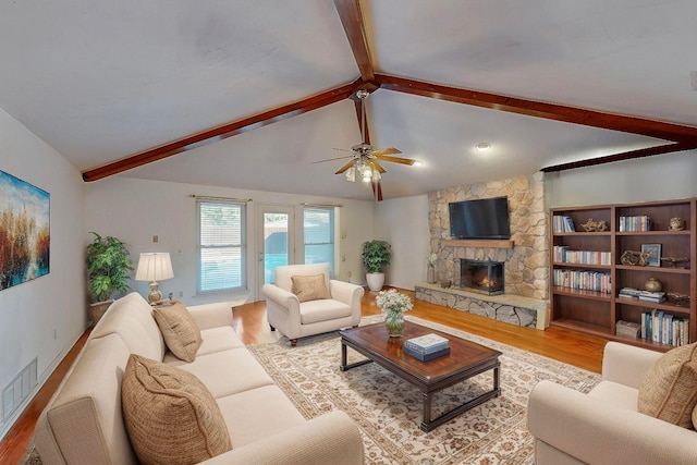 living room with a fireplace, light wood-type flooring, lofted ceiling with beams, and ceiling fan