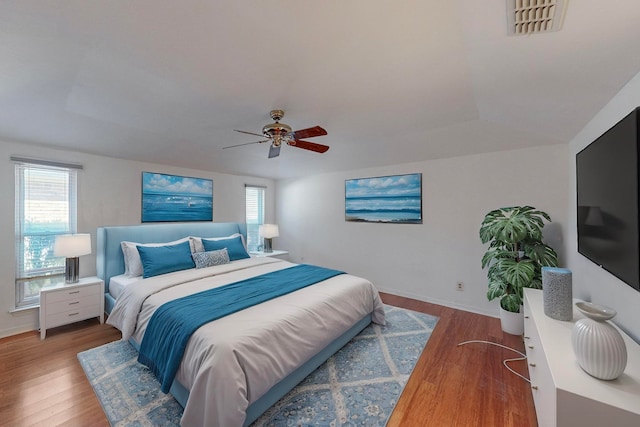 bedroom with ceiling fan, wood-type flooring, and multiple windows