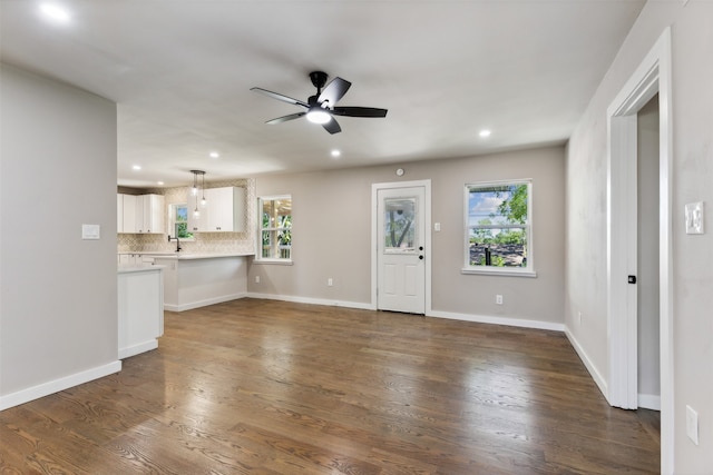 unfurnished living room with dark hardwood / wood-style floors, ceiling fan, a healthy amount of sunlight, and sink