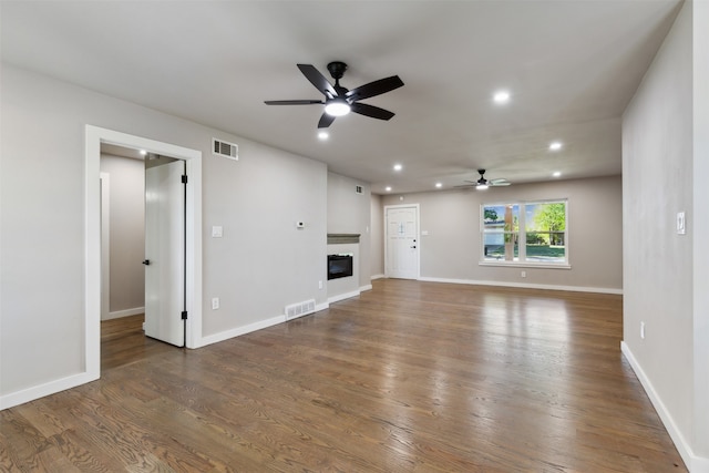 unfurnished living room featuring ceiling fan and dark hardwood / wood-style flooring