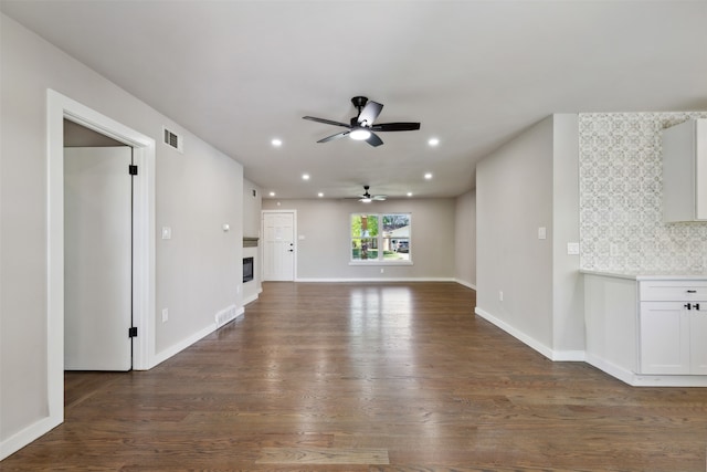 unfurnished living room with ceiling fan and dark wood-type flooring