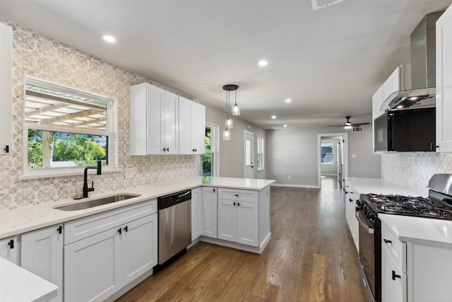 kitchen featuring white cabinetry, dark wood-type flooring, hanging light fixtures, kitchen peninsula, and appliances with stainless steel finishes