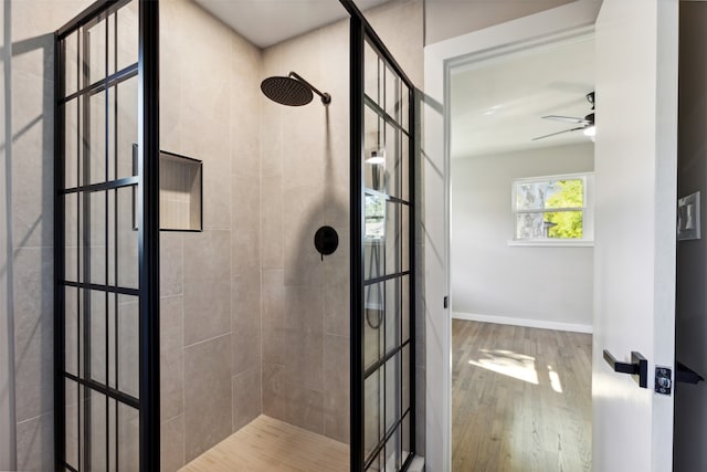 bathroom with tiled shower, hardwood / wood-style flooring, and ceiling fan