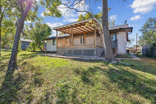 rear view of house with a lawn and a wooden deck