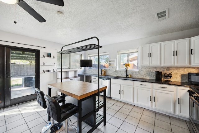 kitchen with visible vents, a sink, stainless steel dishwasher, black microwave, and decorative backsplash