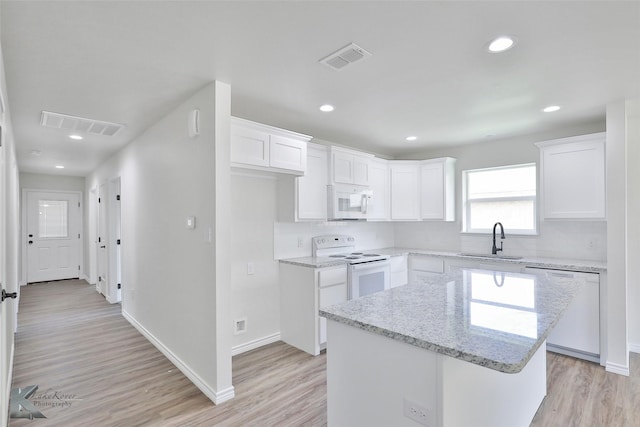 kitchen featuring white appliances, sink, white cabinets, light hardwood / wood-style floors, and a kitchen island