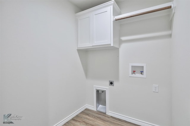 washroom featuring electric dryer hookup, hookup for a washing machine, light hardwood / wood-style flooring, and cabinets