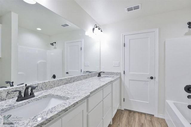 bathroom with hardwood / wood-style floors, vanity, and shower / bathtub combination