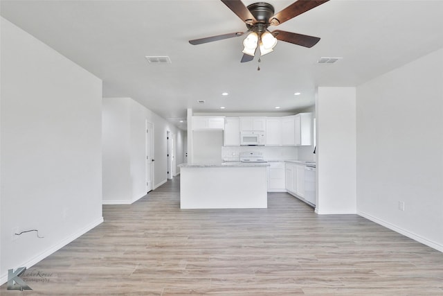 kitchen with white cabinets, a center island, light wood-type flooring, and white appliances